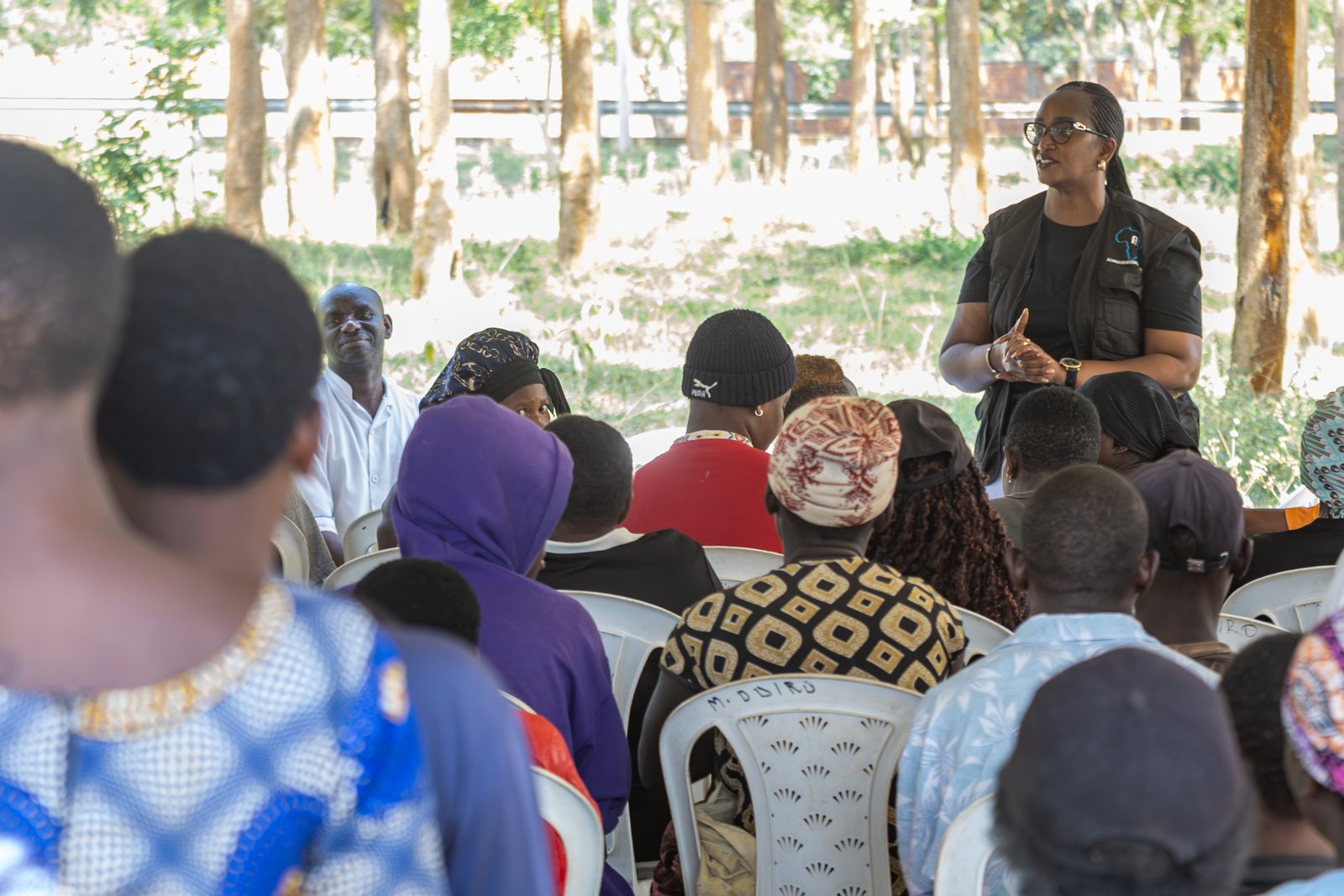 A community health educator addressing a seated community gathering